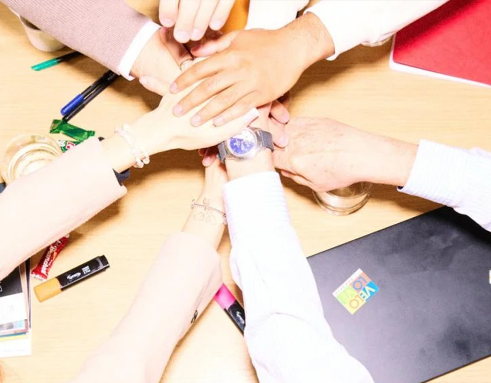 Different people stack their hands as a sign of unity.